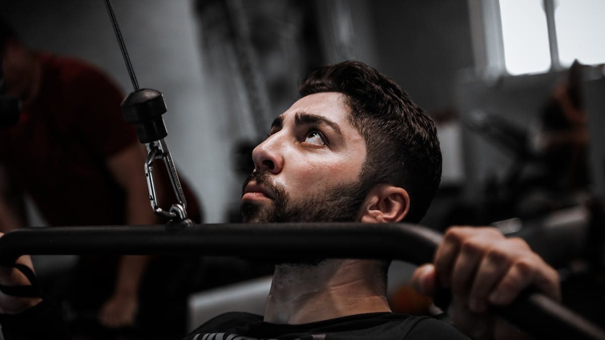 Muscular man working out with determination on gym equipment.